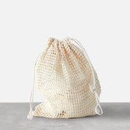 A small, light-colored mesh drawstring bag,  filled with bamboo cotton pads.